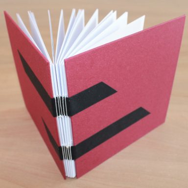 ein aufgeschlagenes handgebundenes Buch mit roten Buchdeckeln